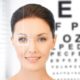 woman smiling at camera in front of Snellen chart, eye exam Western MA, eye care Springfield MA, eye care, eye doctor, Dr. Papale
