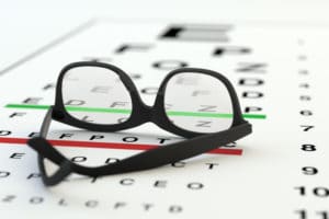 Glasses lying upside down on an eye test chart. 