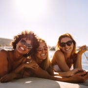 three women smiling and wearing sunglasses laying on a boat, eye protection, sun eye protection, eye care Springfield MA, eye care Western MA