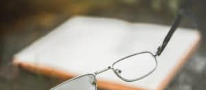 Glasses and a book on blurred background