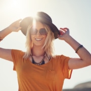 woman holding hat on her head walking through ray of sunshine, eye protection, eye sun protection